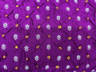 Sarmaşık desenli zengin bir bandhani gaji ipek kumaşı, canlı sarı noktalarla süslenmiş ve geleneksel ama lüks bir cazibe için karışık gümüş dokuma motifleriyle vurgulanmış..