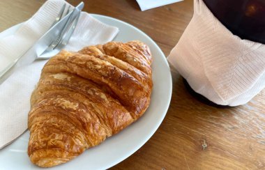 Kahve fincanı ve süt üzerine kruvasan.