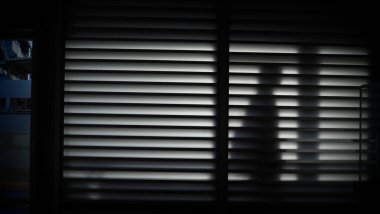 Sabahları penceresi olan siyah elbiseli bir adamın silueti.