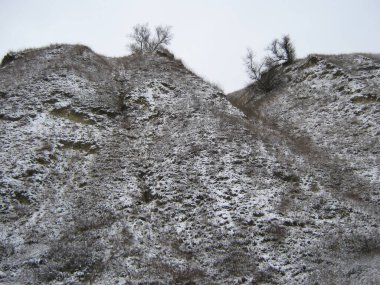 Fotoğraf, alçak dağların karla kaplı yamaçlarını gösteriyor..