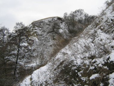 Fotoğraf, alçak dağların karla kaplı yamaçlarını gösteriyor..