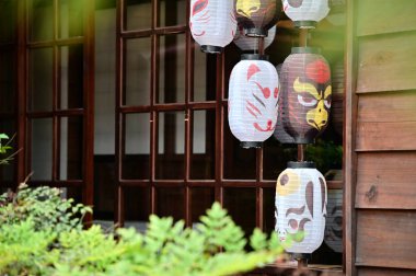 Taiwan - Jan 29, 2024: Paper lanterns hang under the eaves of Japanese-style wooden houses, adorned with various animal images. clipart