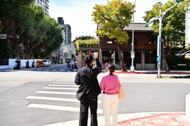 Tayvan-01.29.24: Bir çift trafik ışığında 'Rongjin Gorgeous Times' ın fotoğrafını çekiyor. Bir zamanlar Taipei Hapishanesi 'nin Japon sömürge döneminde yaşadığı bir park. Yenilenmiş, artık bir kültür parkı..