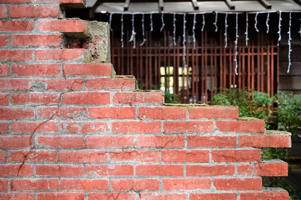 stock image Taiwan - Jan 29, 2024: Sunlight illuminates red brick walls on a sunny spring day. A serene Japanese wooden house stands within the enclosure, emitting a quaint and elegant atmosphere.