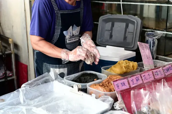 Tayvan - 09 Temmuz 2024: Yeni yapılmış mochi 'nin içini dolduran bir pazar satıcısı paketi. Bu geleneksel glutinous pilav ziyafeti Tayvan ve Asya 'da eşsiz dokusu ve çeşitliliği nedeniyle kutsanmıştır..