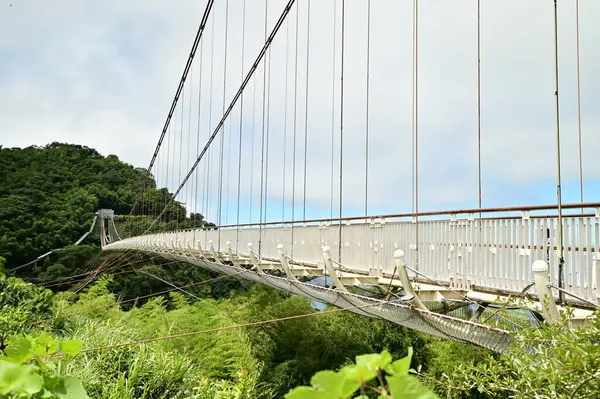 Stock image A close-up of the Taiping Suspension Bridge set against a clear blue sky with white clouds on a sunny day. The scene showcases the stunning high-altitude landscape of Taiwan.