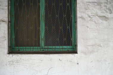 The dusty white wall, paired with a green-framed window and weathered iron grilles, captures the aging charm of a soon-to-be-redeveloped home. clipart