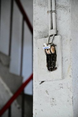 A ceramic knife switch on the wall of a residential building, soon to undergo redevelopment, highlights its significance in Taiwan's electrical appliance history. clipart