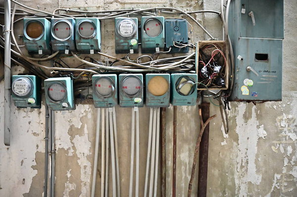 Выветриваемая стена старого здания, предназначенного для реконструкции, имеет традиционные электрические счетчики, некоторые сломанные или пустые, рассказывающие истории о прошлом полезности.