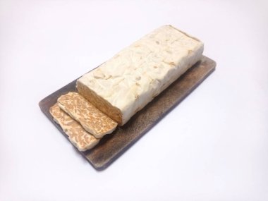 Ahşap kesme tahtasındaki çiğ fırtınayı kapat ve beyaz arkaplanda izole edilmiş bir şekilde kes. Endonezya yemeği tempeh