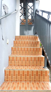 Kırmızı tuğla motifli seramik ve gri demir tırabzanlarla kalıcı ev merdivenleri.