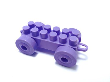 Tekerlekleri ve lastikleri beyaz arka planda izole edilmiş plastikten yapılmış tek bir mor tren bloğu.