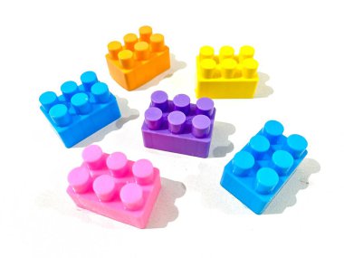 Beyaz arka planda plastikten yapılmış renkli yapı taşı oyuncakları grubu
