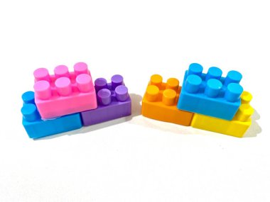 Beyaz arka planda plastikten yapılmış renkli yapı taşı oyuncakları grubu