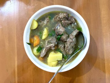 Bir kase Sop Buntut ya da havuçlu ve ahşap masadaki patatesli Oxtail çorbası. Endonezya geleneksel yemekleri