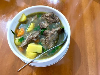 Bir kase Sop Buntut ya da havuçlu ve ahşap masadaki patatesli Oxtail çorbası. Endonezya geleneksel yemekleri