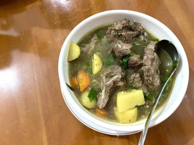 Bir kase Sop Buntut ya da havuçlu ve ahşap masadaki patatesli Oxtail çorbası. Endonezya geleneksel yemekleri