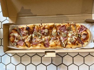 Biftek sosisli, sucuklu, mozzarella peynirli, domates soslu ve mantarlı uzun pizza.