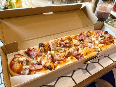 Biftek sosisli, sucuklu, mozzarella peynirli, domates soslu ve mantarlı uzun pizza.