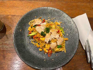 Baharatlı spagetti, tavuk eti, kırmızı biber, omlet ve taze soğan. Lüks bir tabakta servis ediliyor.