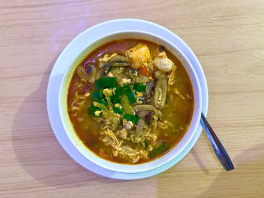 Yumurtalı, mantarlı ve beyaz kasede servis edilen kırmızı baharatlı kremalı erişte çorbası.