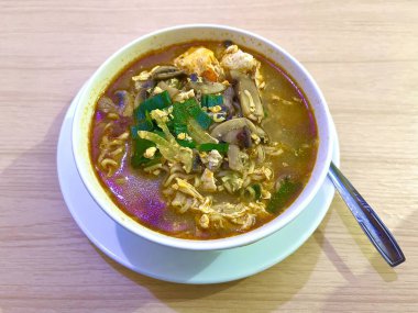 Yumurtalı, mantarlı ve beyaz kasede servis edilen kırmızı baharatlı kremalı erişte çorbası.