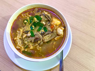 Yumurtalı, mantarlı ve beyaz kasede servis edilen kırmızı baharatlı kremalı erişte çorbası.