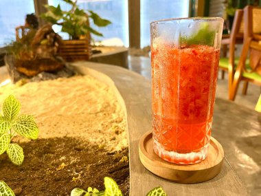 Süslü bir restoranda, üzerinde nane yaprakları olan bir bardak çilekli kabak.