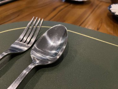 Restorandaki çatal ve kaşıkla gümüş paslanmaz çelik çatal bıçak takımının yakın görüntüsü.