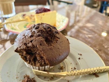 Çikolatalı kek ve çikolatalı pasta seramik küçük bir tabakta ve altın çatalla servis ediliyor.