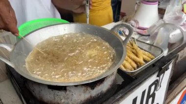 Telur Gulung hazırlayıp satan bir adam ya da kızgın yağda kızartılmış yumurta rulosu satan bir adam. Sokak yemekleri konsepti.