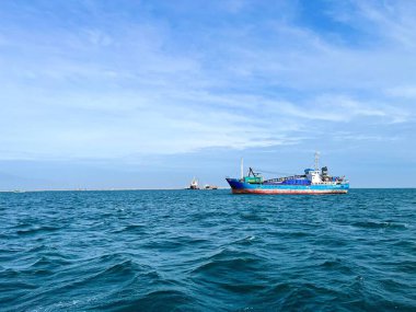 Ufukta güzel mavi gökyüzüyle denizin ortasında yelken açan vinci olan balıkçı teknesinin yan görüntüsü 