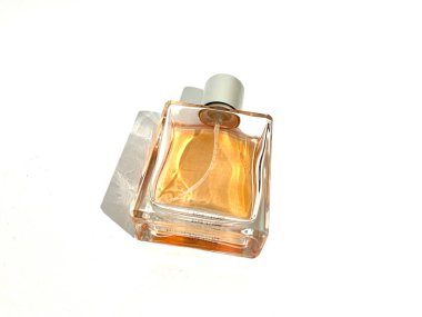 Tek bir küp şeklindeki lüks parfüm şişesi sprey pompası ve beyaz arka planda izole edilmiş turuncu sıvı.