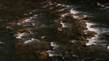 Fast flow of water on a mountain river. Beautiful mountain river. Brown stones are visible in the transparent mountain river.