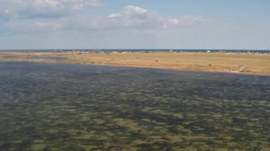 İnsanlar denizde uçurtma gibi uçuyor. Rüzgar sporcuyu deniz dalgaları boyunca taşır. Çok renkli paraşütler.