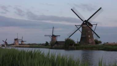 Hollanda 'nın Kinderdijk köyünde günbatımında güzel ahşap yel değirmenleri. Rüzgar değirmenleri esiyor. Güzel Hollanda kanalları suyla doludur. Güzel gün batımı.