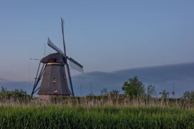 Hollanda 'nın Kinderdijk köyünde günbatımında güzel ahşap yel değirmenleri. Rüzgar değirmenleri esiyor. Güzel Hollanda kanalları suyla doludur. Güzel gün batımı.