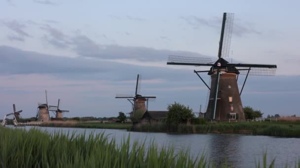 キンダーダイクのオランダ村の日没時に美しい木製の風車 風車は風に乗って走る 美しいオランダの運河には水が満ちています 美しい夕日 — ストック動画