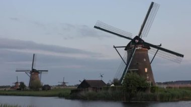Hollanda 'nın Kinderdijk köyünde günbatımında güzel ahşap yel değirmenleri. Rüzgar değirmenleri esiyor. Güzel Hollanda kanalları suyla doludur. Güzel gün batımı.