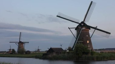 Hollanda 'nın Kinderdijk köyünde günbatımında güzel ahşap yel değirmenleri. Rüzgar değirmenleri esiyor. Güzel Hollanda kanalları suyla doludur. Güzel gün batımı.