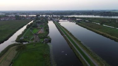 Yukarıdan güzel bir manzara. Hollanda 'nın Kinderdijk köyünde günbatımında güzel ahşap yel değirmenleri. Rüzgar değirmenleri esiyor. Güzel Hollanda kanalları suyla doludur..