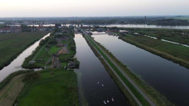 Yukarıdan güzel bir manzara. Hollanda 'nın Kinderdijk köyünde günbatımında güzel ahşap yel değirmenleri. Rüzgar değirmenleri esiyor. Güzel Hollanda kanalları suyla doludur..
