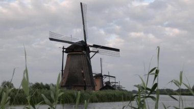 Hollanda 'nın Kinderdijk köyünde günbatımında güzel ahşap yel değirmenleri. Rüzgar değirmenleri esiyor. Güzel Hollanda kanalları suyla doludur. Güzel gün batımı.