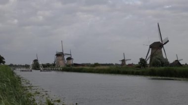 Hollanda 'nın Kinderdijk köyünde günbatımında güzel ahşap yel değirmenleri. Rüzgar değirmenleri esiyor. Güzel Hollanda kanalları suyla doludur. Güzel gün batımı.