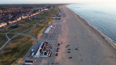 Yazın Katwijk aan Zee sahilinde güzel bir uçuş. İnsanlar deniz kenarında dinleniyor. Turistler için evler. Plaj şemsiyeleri, gezintiler, denizde yüzen insanlar. Hollanda 'da bir plaj. Kuzey Denizi.