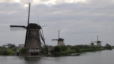 Hollanda 'nın Kinderdijk köyünde günbatımında güzel ahşap yel değirmenleri. Rüzgar değirmenleri esiyor. Güzel Hollanda kanalları suyla doludur. Güzel gün batımı.