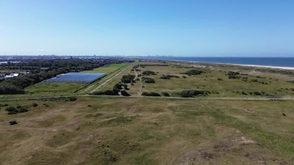 Kijkduin和大海的俯瞰 飞过绿草覆盖的田野和海滨的建筑物 背景中房屋的屋面 北海附近的四合院的视野 — 图库视频影像