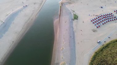 Yazın Katwijk aan Zee sahilinde güzel bir uçuş. İnsanlar deniz kenarında dinleniyor. Turistler için evler. Plaj şemsiyeleri, gezintiler, denizde yüzen insanlar. Hollanda 'da bir plaj. Kuzey Denizi.