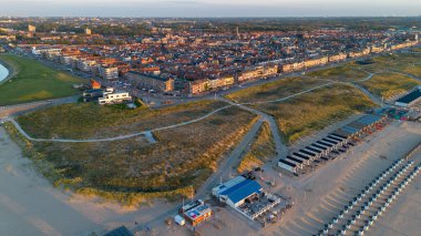 Yazın Katwijk aan Zee sahilinde güzel bir uçuş. İnsanlar deniz kenarında dinleniyor. Turistler için evler. Plaj şemsiyeleri, gezintiler, denizde yüzen insanlar. Hollanda 'da bir plaj. Kuzey Denizi.