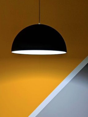 Sarı duvarın arkasında bir lamba. Gri duvar ve beyaz şerit. Kafede, restoranda, dükkanda ışıklandırma. Odanın güzel tasarımı. Odanın içinde..